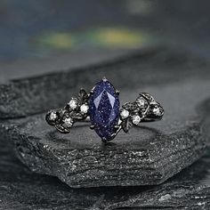 a ring with a blue stone surrounded by white diamonds on top of a black rock