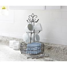 a kitchen counter with dishes in a wire basket on it's side and a white tile backsplash behind it