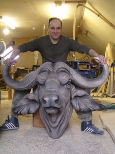 a man standing next to a statue of a bull with horns on it's head