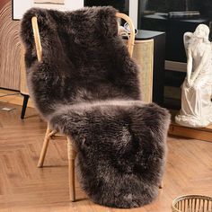 two chairs with fur on them sit in front of a mirror and statue next to it