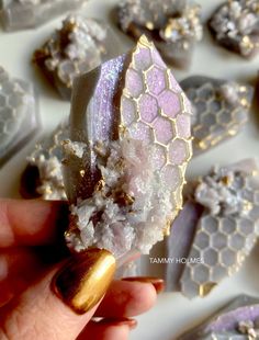 a hand holding a piece of purple and gold glittered cake next to other cakes