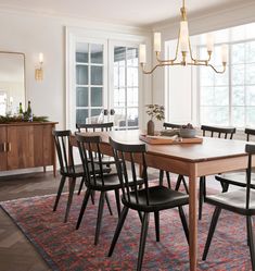 a dining room table with six chairs and a rug on the floor in front of it