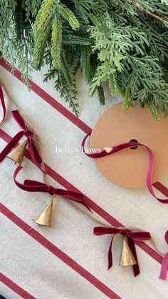 a christmas tree with red ribbon and gold bells on it next to a pair of scissors