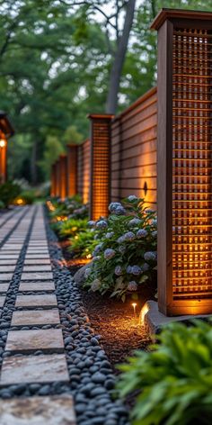 an outdoor walkway lit up with lights and plants on either side, surrounded by stone pavers