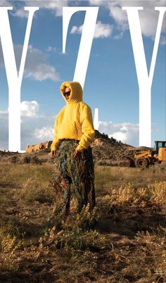 a man in a yellow hoodie is standing in the grass