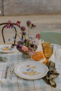 the table is set with plates, silverware and flowers