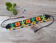 a beaded lanyard on a wooden table next to a plant