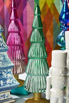 colorful glass christmas trees on display in front of multicolored wall paper and other decorative items