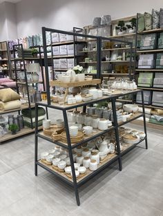 a display case filled with lots of white dishes and cups on wooden trays in a store