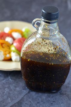 a bottle of liquid sitting on top of a table next to a plate of food