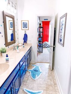 a bathroom with blue and white decor on the vanity, rugs and mirror in it