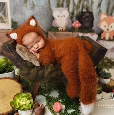 a baby sleeping in a wooden chair surrounded by fake plants and other stuffed animal toys