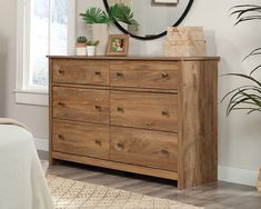 a bedroom with a bed, dresser and mirror on the wall next to potted plants