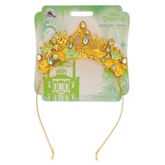 Attend a royal coronation for your Carnivale Queen with this bejeweled tiara. Lotus blossoms, lily pads, and faceted gems offer fanciful filigree for this crowning glory of any Tiana costume. Tiana silhouette and bayou filigree. Accented by faceted gems. Metal headband with protective tips. Golden finish. Genuine, Original, Authentic Disney Store Product. Princess Style Gold Crown With Structured Shape, Gold Princess Crown With Structured Shape, Princess Style Gold Crown With Tall Shape, Gold Princess Crown With Pinched Shape, Princess Style Jewelry With Tall Crown Design, Princess Tiana Tiara, Tiana Silhouette, Tiana Tiara, Tiana Costume