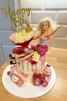 a barbie doll sitting on top of a cake next to bottles and condiments