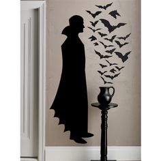 the silhouette of a man in a hat and cape stands next to a wall with bats on it