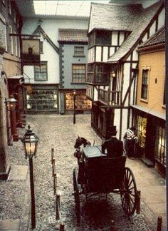 an old fashioned horse drawn carriage on a cobblestone street in the middle of town