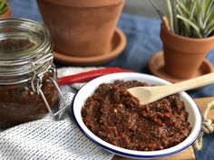 a bowl full of chili paste next to some potted plants and a wooden spoon