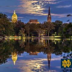 the full moon is reflected in the still waters of this city's lake at twilight