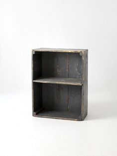 an old wooden shelf with two shelves on each side, against a white wall background