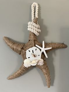 a starfish hanging on the wall with rope and seashells attached to it