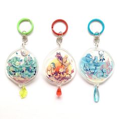 three keychains with cartoon characters on them sitting next to each other in front of a white background