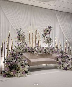 a couch covered in flowers and candles next to a wall with white draping