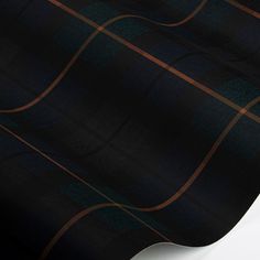 the black and brown plaid fabric is laying on top of a white surface with an orange stripe