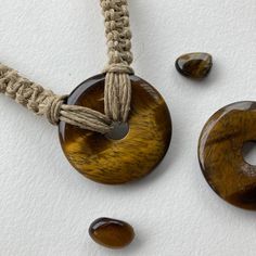 Donut gemstone design can be warn as necklace or choker! This shimmery tiger eye donut stone is quite large at 40mm wide and about 6mm thick (photos show front and back). The hemp chain is braided in a square knot style and is about 18 inches long (can be shortened to a choker length on request). Attaches in the back with a wooden bead through knotted loop. Handmade Brown Cord Jewelry, Handmade Cord Jewelry Gift, Handmade Cord Spiritual Jewelry, Brown Adjustable Cord Jewelry For Healing, Spiritual Cord Jewelry For Gifts, Adjustable Amber Crystal Necklaces, Adjustable Amber Crystal Necklace Round, Adjustable Round Amber Crystal Necklace, Adjustable Amber Crystal Necklace