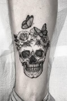 a skull with flowers and butterflies on it's head is seen in this black and white photo