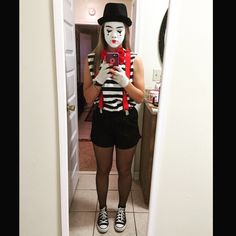 a woman taking a selfie in front of a mirror wearing a clown mask and holding a cell phone