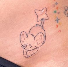 a small elephant tattoo on the side of a woman's stomach with stars around it