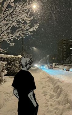 a man walking down a snow covered street at night