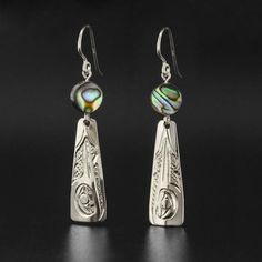 This listing is for one pair of hand-engraved sterling earrings by First Nations artist Carrie Matilpi. The price includes the shipping fee, except for shipments that must be sent overseas. Each pair is hand-engraved and will differ slightly from the images included here. Each pair measures 1.25" long by 0.5" wide and there are two options to choose from:Hummingbird with Abalone - symbol of joy and good luckWolf with Moonstone - symbol of family and communicationPlease allow 2-3 weeks for delive Silver Etched Round Earrings, Engraved Sterling Silver Drop Earrings, Silver Engraved Round Earrings, Engraved Teardrop Earrings For Gift, Sterling Silver Etched Jewelry For Gifts, Sterling Silver Etched Jewelry As Gift, Polished Sterling Silver Earrings As A Gift, Engraved Sterling Silver Dangle Jewelry, Etched Sterling Silver Jewelry As Gift