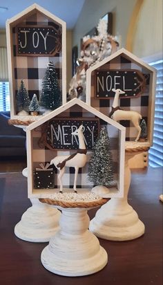 three small wooden houses decorated with christmas decorations and reindeer figurines on top of a table