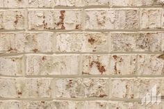 an old brick wall that has been painted white and brown with some rust on it