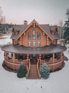 a large wooden house in the middle of snow covered ground with stairs leading up to it