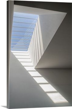 an empty room with white walls and shadows on the floor, as well as a skylight