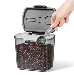 a person is scooping coffee beans into a container with a spoon in the shape of a box