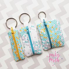 three zippered purses are sitting next to each other on a white surface with blue and yellow polka dots