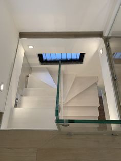 an empty room with glass stairs and skylight