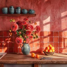 a vase filled with flowers sitting on top of a wooden table next to oranges