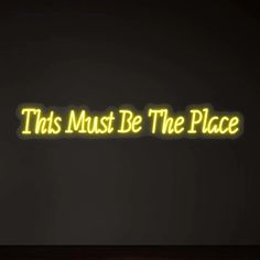 this must be the place neon sign in front of a black background with yellow lettering