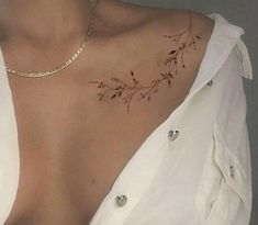 a woman with a tattoo on her chest is wearing a white shirt and silver necklace