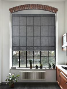 a kitchen with a brick wall and large window in the center, next to a radiator