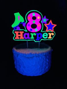 a birthday cake that has the number eight on it and is lit up with neon colors