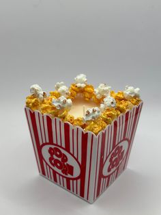 a red and white striped box with popcorn on the inside is lit by a candle