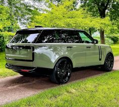 a range rover parked on the side of a road in front of some green trees