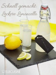 a bottle of water and two glasses with lemons on a black slate tray next to a banana