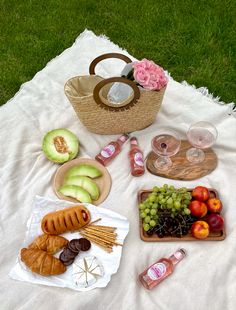 a picnic is set out on the grass with fruit, bread and watermelon